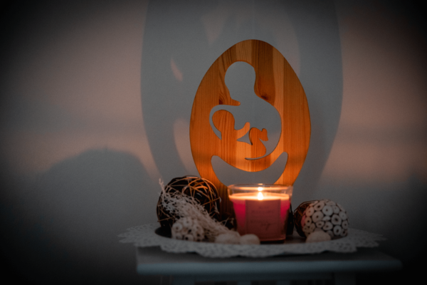 Holzdekoration zeigt Mutter mit ihrem Kind und einer Kerze daneben